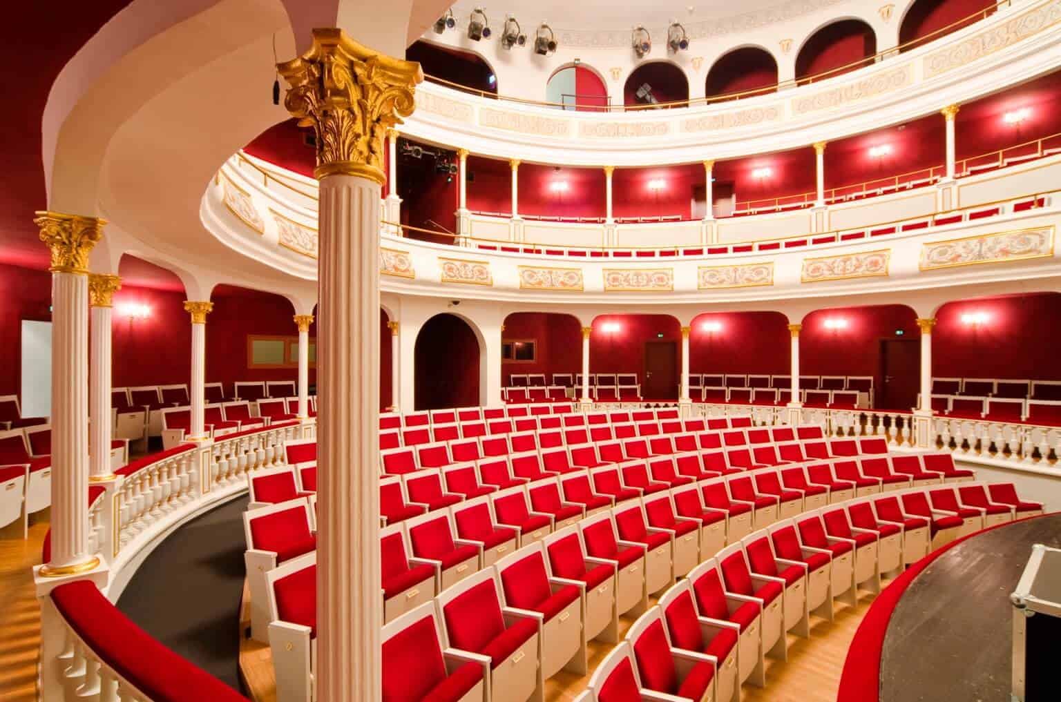 Innenansicht des Stadttheaters Aschaffenburg mit roten Sitzen, Logen und Säulen, bereit für Konzerte.
